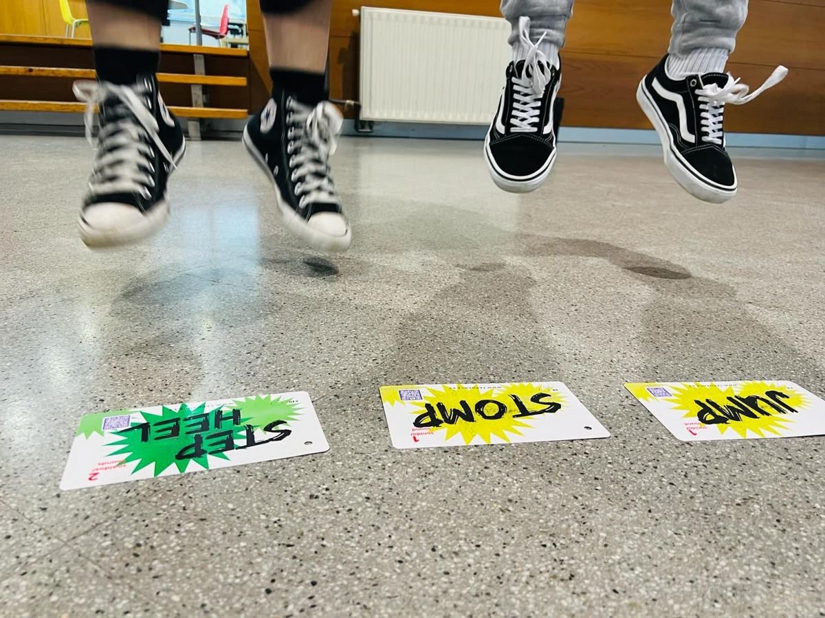 Pies saltando con zapatillas sobre tarjetas de pasos en el suelo de un colegio
