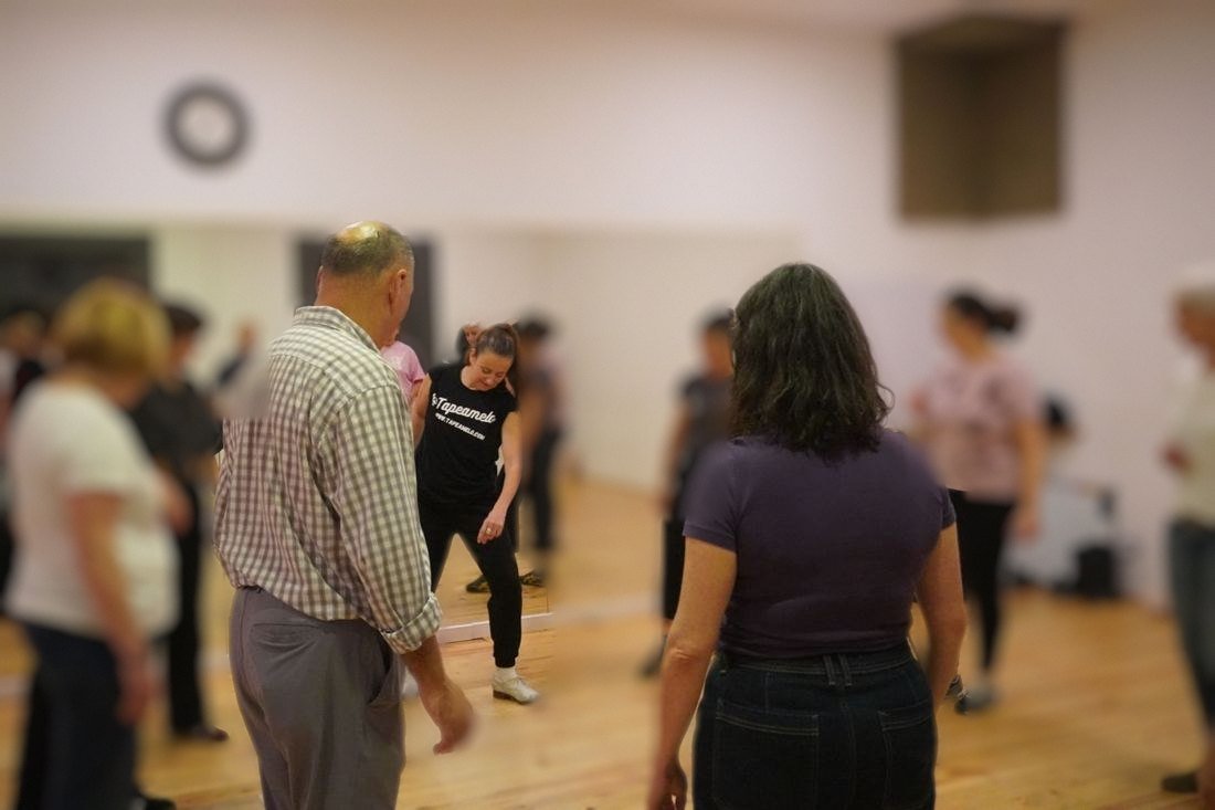 Grupo de adultos aprendiendo pasos en una sala de danza con espejos
